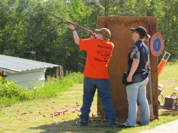 Male shotgunner taking aim, female coach looking on